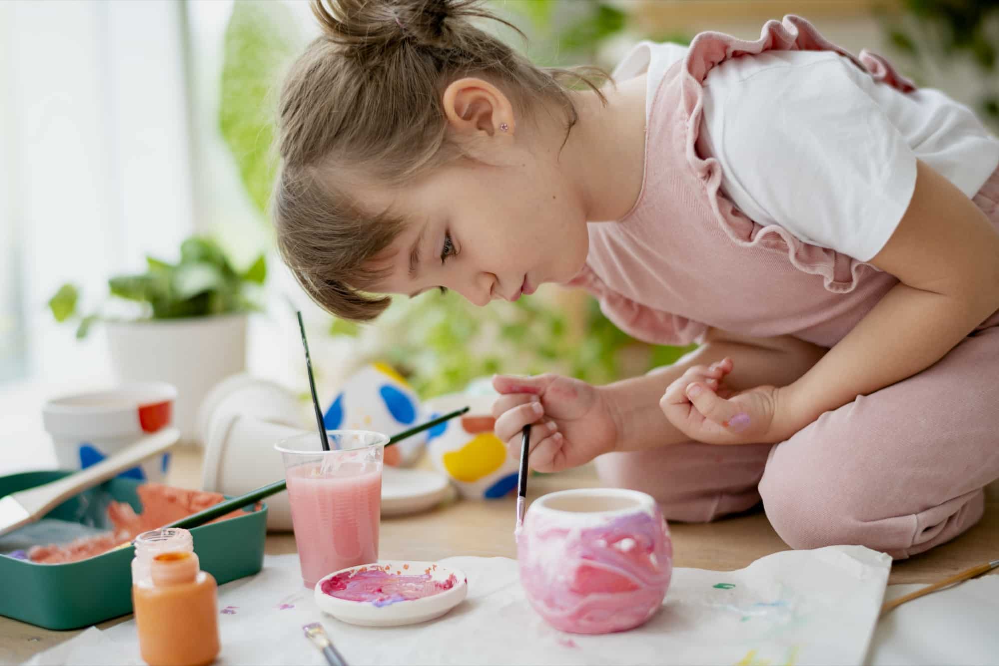 Un enfant peint un pot de fleurs en atelier créatif