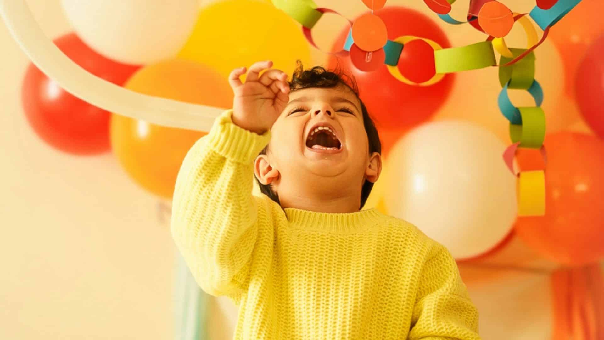 Un enfant qui rit sous les ballons et les guirlandes d'un anniversaire