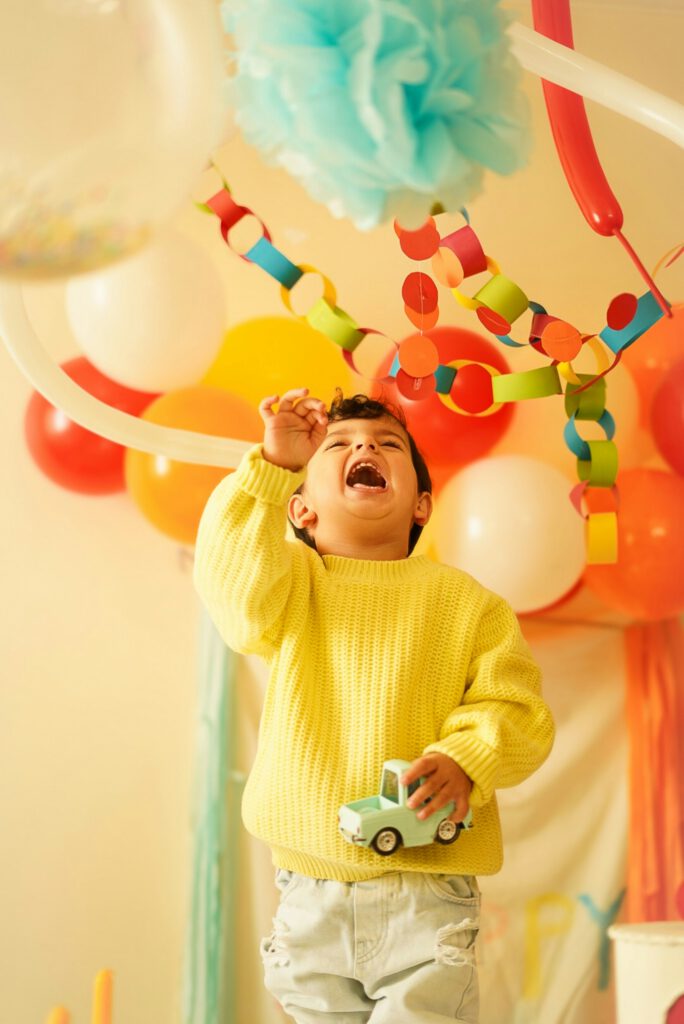 Un enfant qui rit sous les ballons et les guirlandes d'un anniversaire