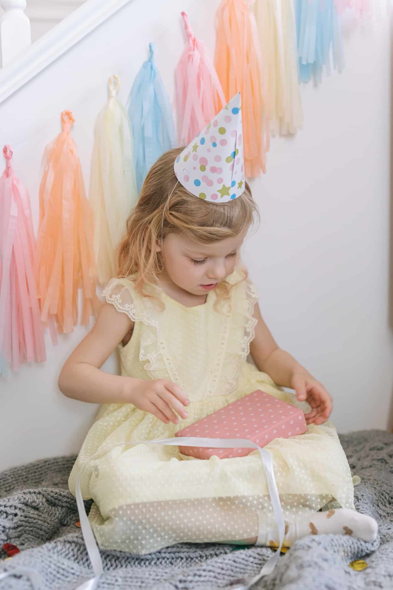 Une enfant ouvre son cadeau, chapeau de fête sur la tête