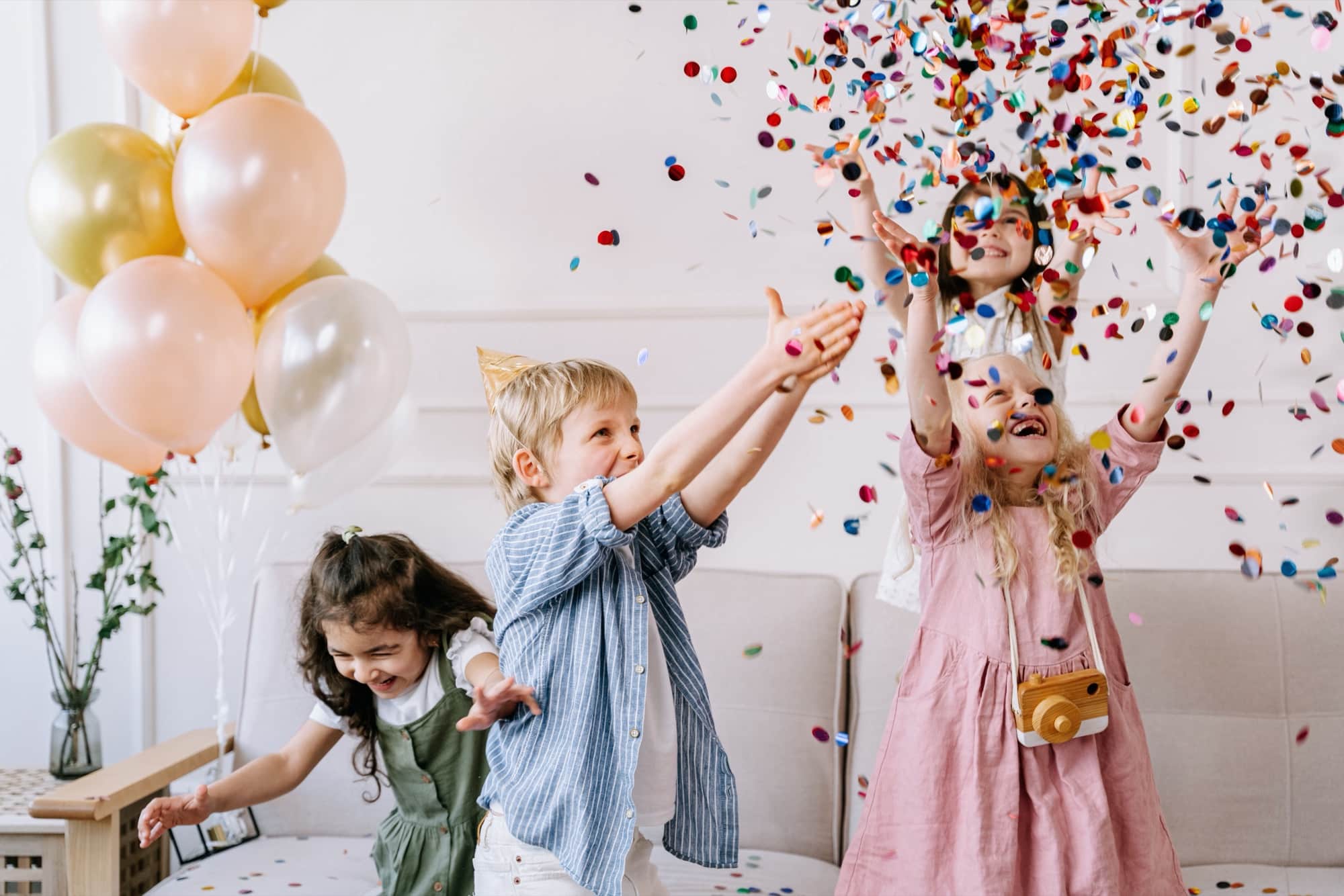 Des enfants lancent des confettis en riant à un anniversaire