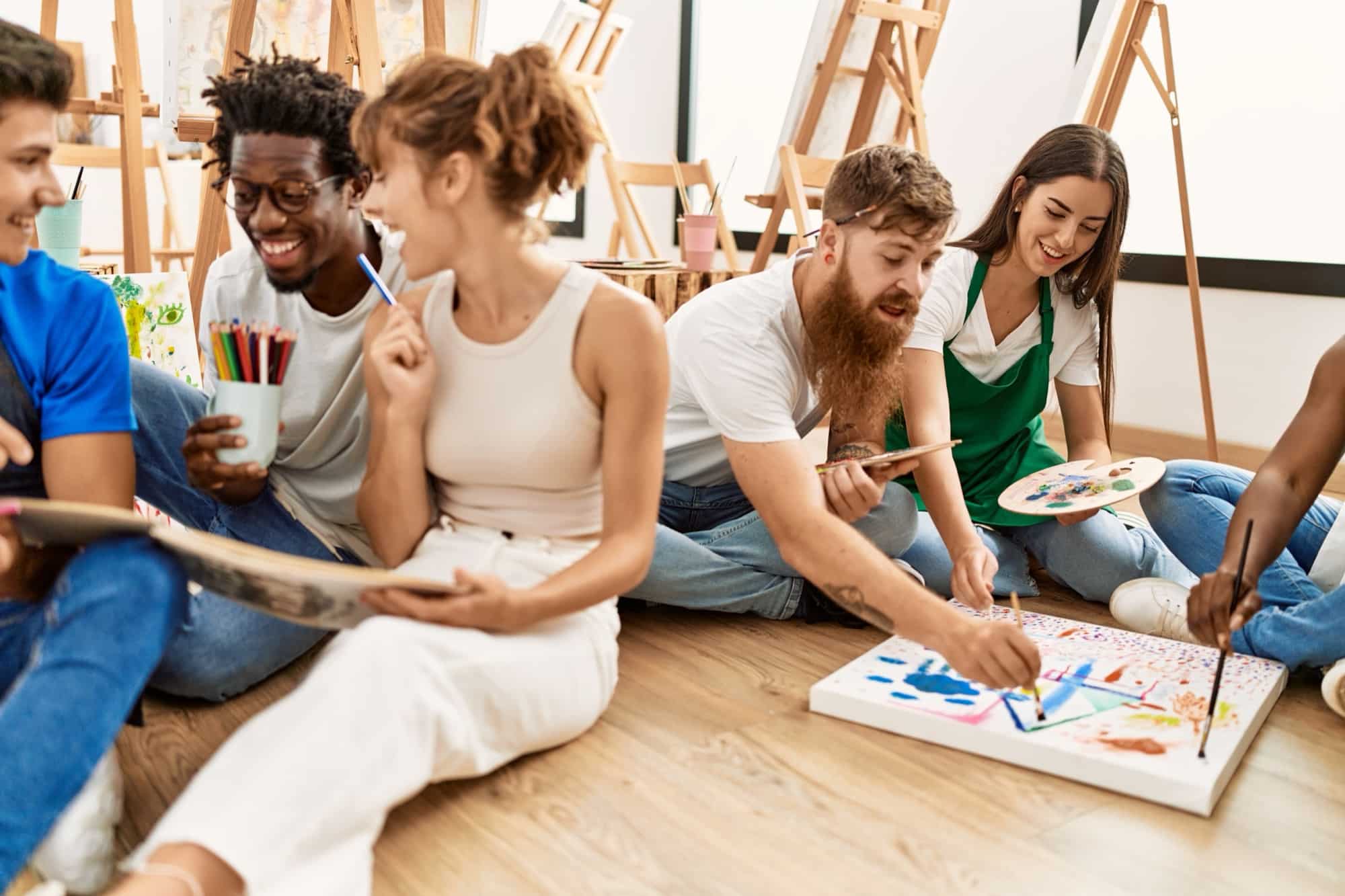Un groupe d'amis peignent ensemble au sol d'un atelier créatif